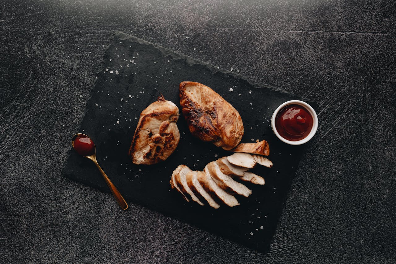 Delicious roasted chicken breast on slate with sauce, ready to serve.
