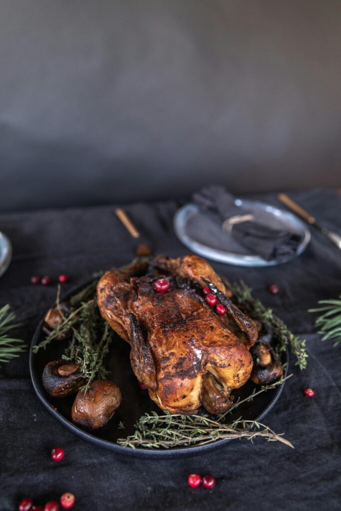 pexels photo 5702776 5702776 Delicious roasted turkey garnished with fresh herbs and cranberries, perfect for holiday feasts.